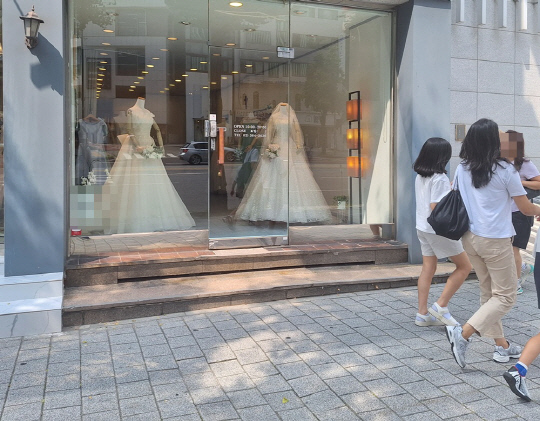 시민들이 지난 13일 오후 서울 아현동 웨딩드레스 거리에 위치한 한 웨딩숍 앞을 지나가고 있다.<박상길 기자>